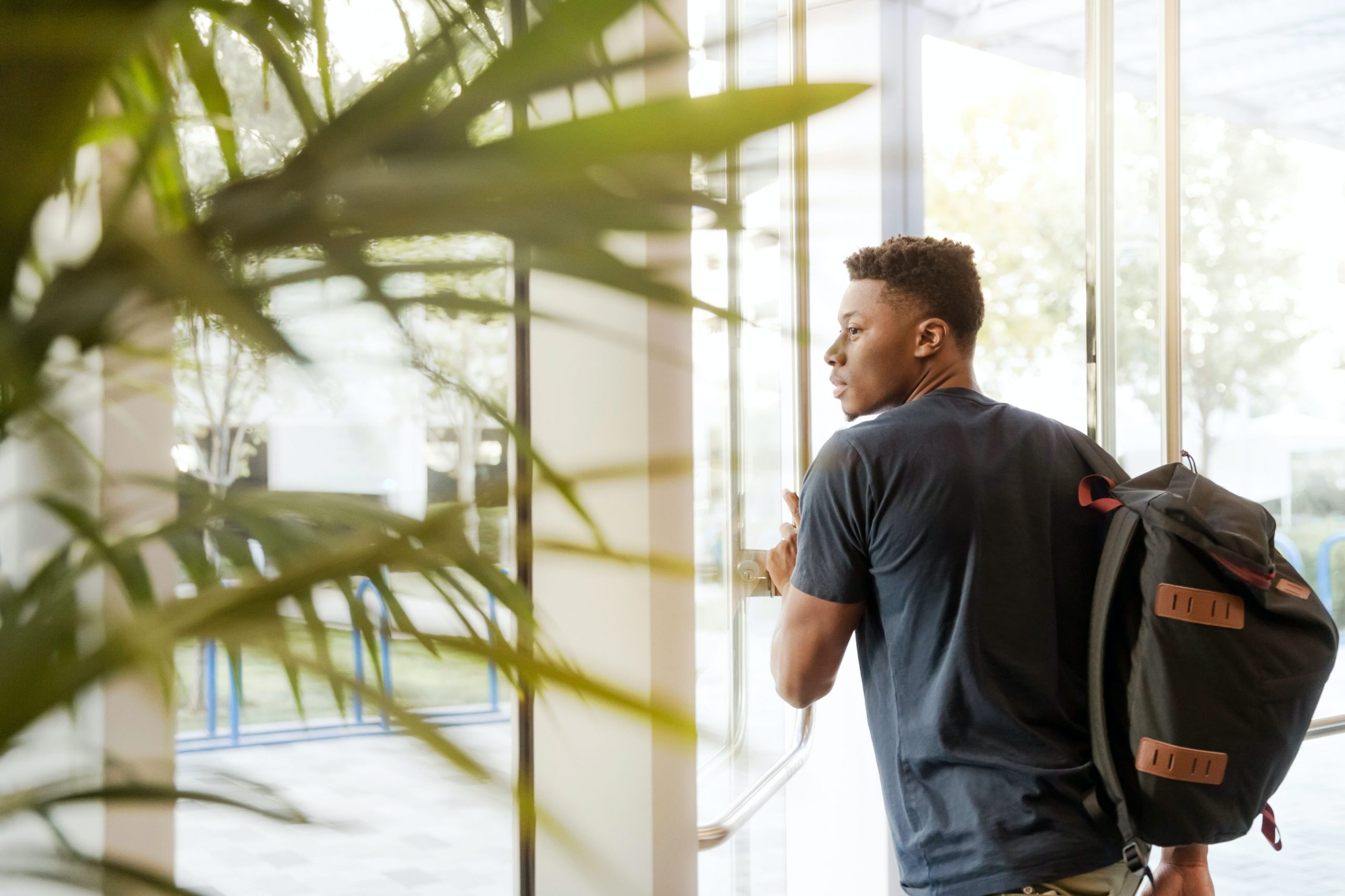 man-looking-outside-window-carrying-black-and-brown-backpack-1251861-copy-min-scaled